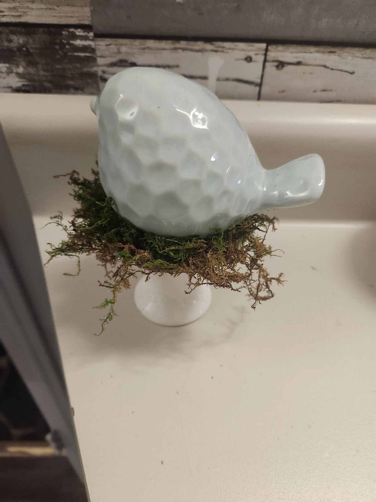 Light blue bird on pedestal
