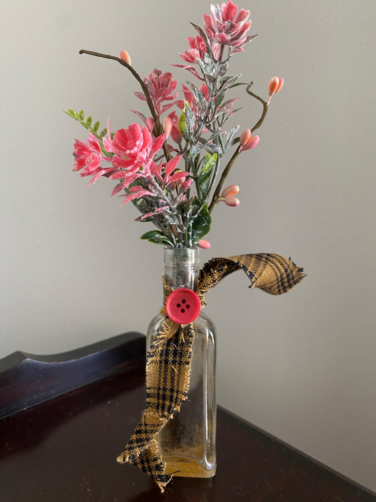 Old glass bottle with pink succulents and button