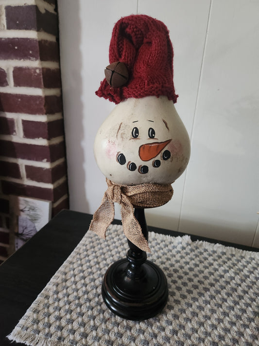 Snowman on pedestal with red hat